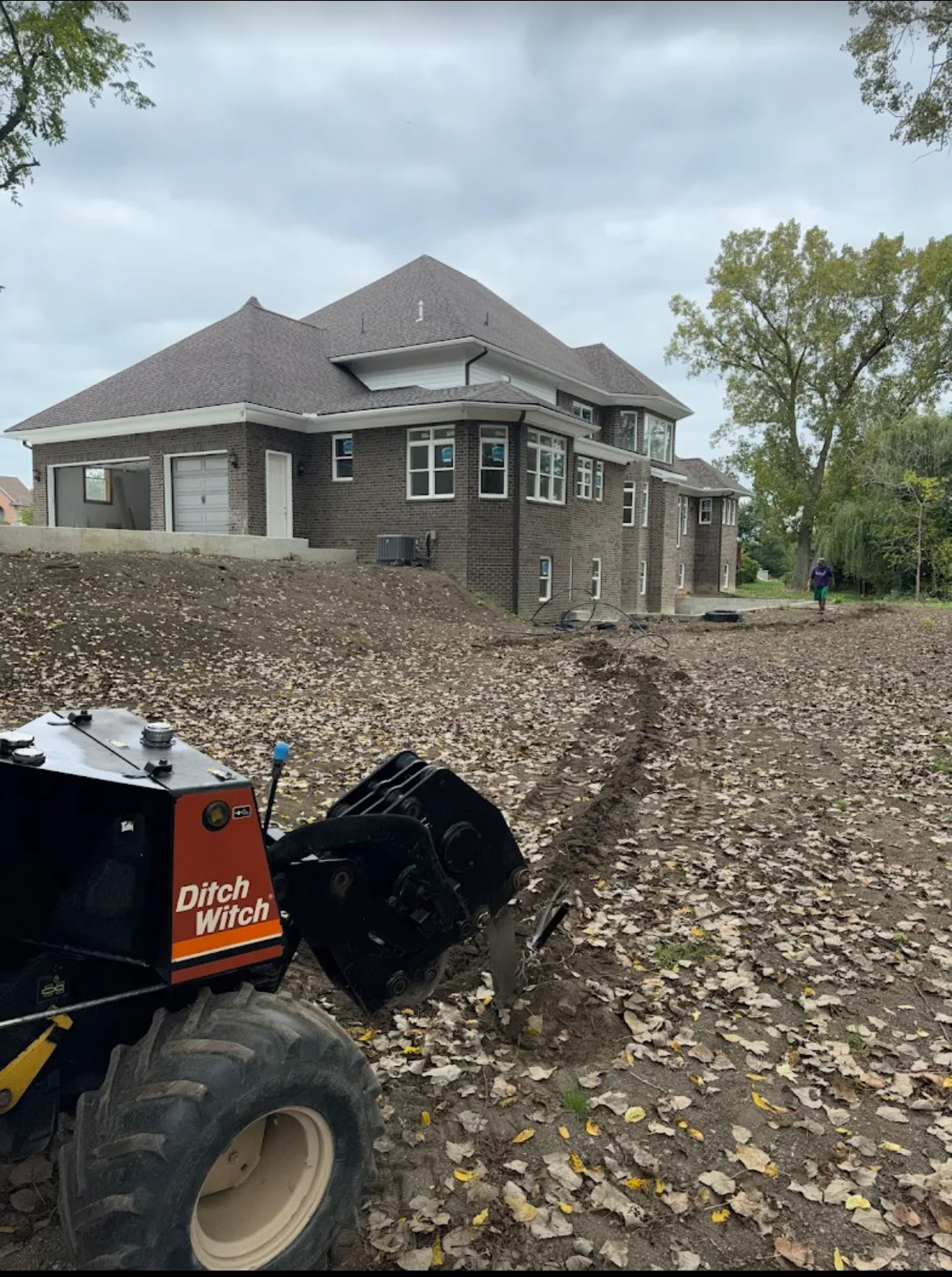 Elite Sprinkler Systems technician installing new irrigation system with Ditch Witch in Michigan