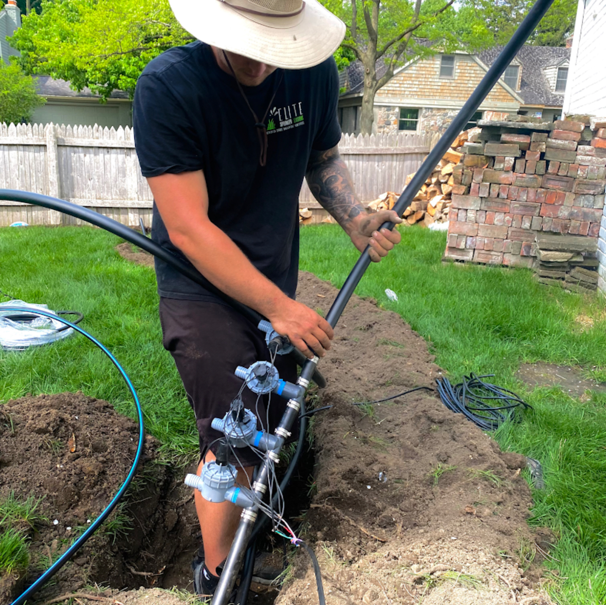 Elite Sprinkler Systems technician installing irrigation valves at a Michigan residential property.