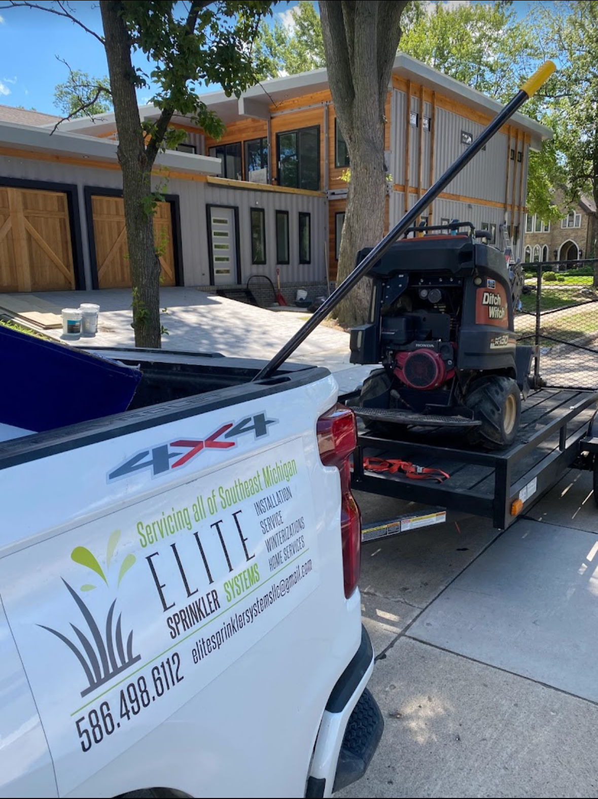 Elite Sprinkler Systems service truck with equipment trailer arriving for sprinkler winterization in Michigan.